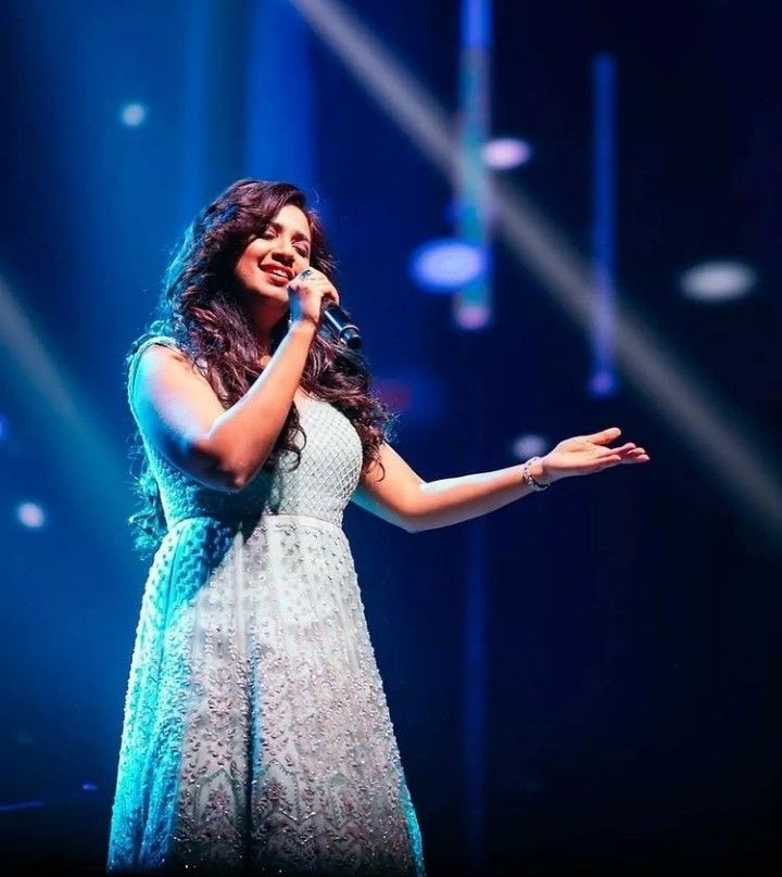 a woman standing on stage holding a microphone in her hand and singing into the microphone