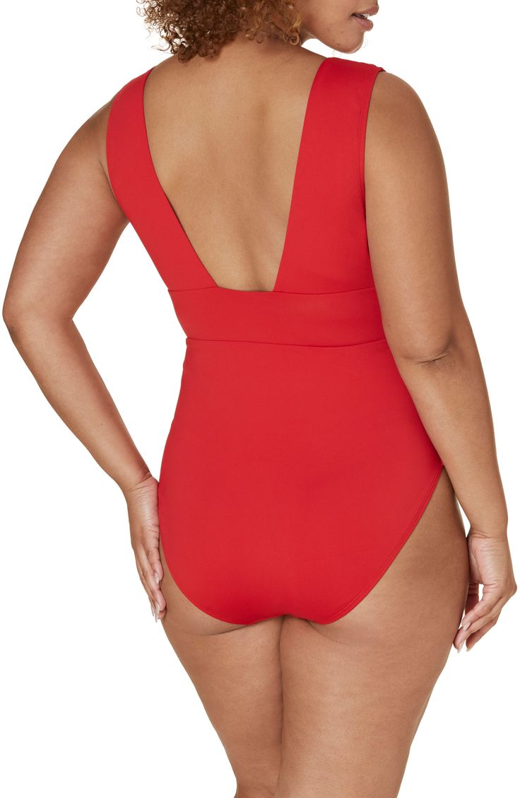 a woman in a red one piece swimsuit with her back turned to the camera