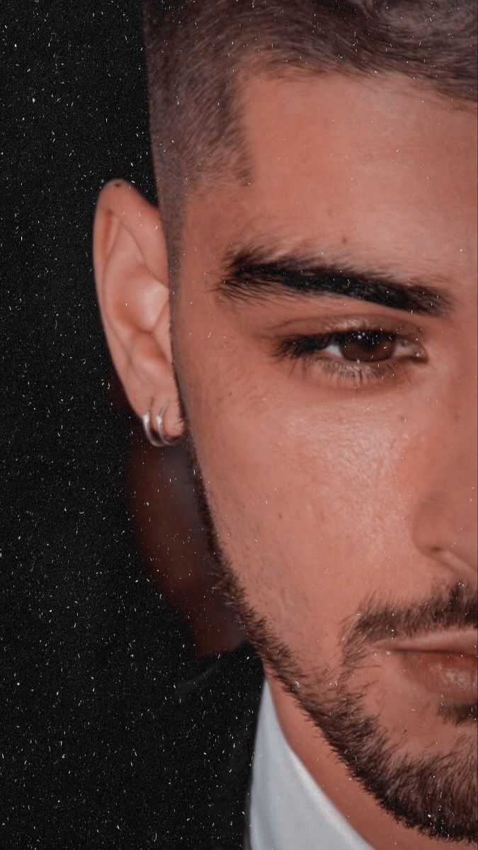 a close up of a person wearing a suit and tie with ear rings on his ears