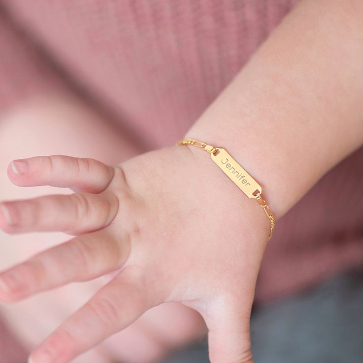 a child's hand with a gold bracelet on it