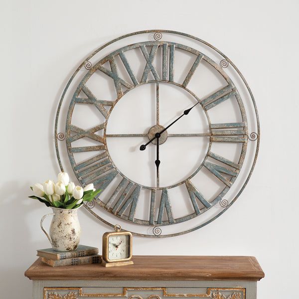 a large metal clock sitting on top of a table next to a vase with flowers