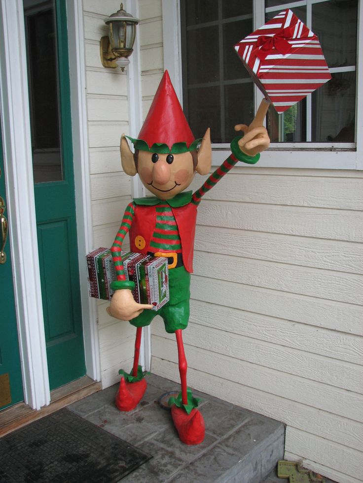 an inflatable christmas elf holding a candy box on the front steps of a house