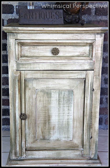 an old white wooden cabinet sitting in front of a brick wall with the words whimsical passage written on it