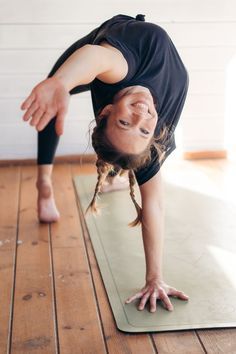 a woman doing a handstand on a yoga mat