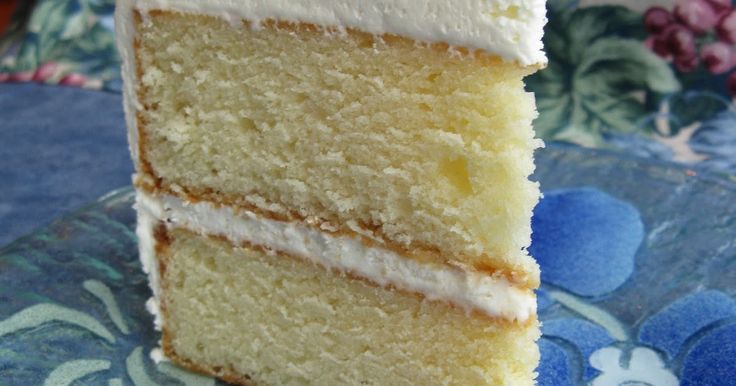 a slice of cake with white frosting sitting on top of a blue table cloth