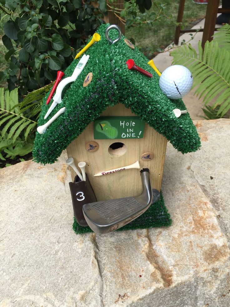 a golf themed birdhouse is sitting on a rock