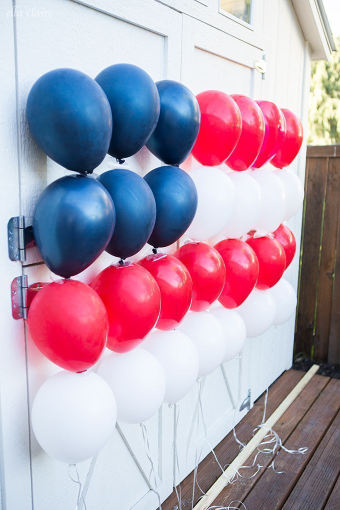 red, white and blue balloons are hanging on the wall