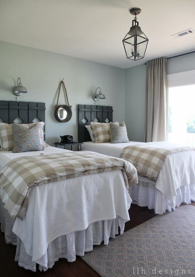 two beds in a bedroom with plaid comforter and pillows on the headboards,