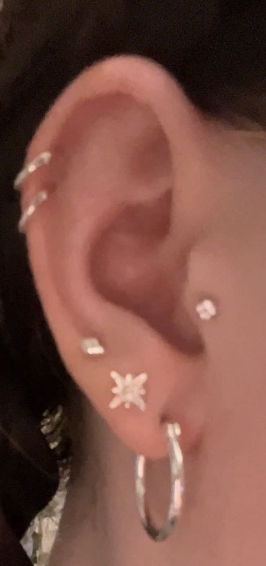 a close up of a person's ear with small white flowers on the side