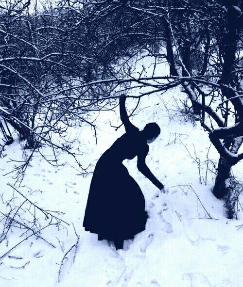 black and white photograph of a woman in the snow reaching up to grab something out of her hand