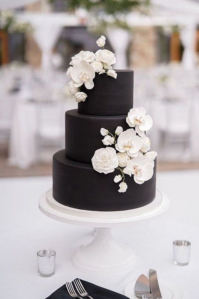 a black and white wedding cake with flowers on top