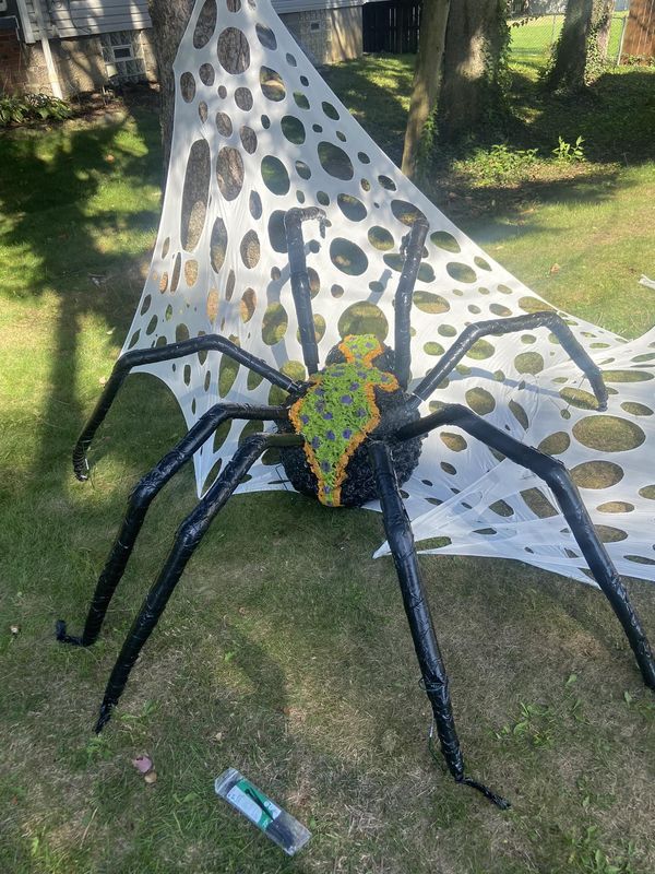 a large spider sculpture sitting on top of a lush green field