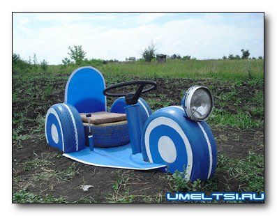 a blue and white toy car sitting in the middle of a field with wheels on it