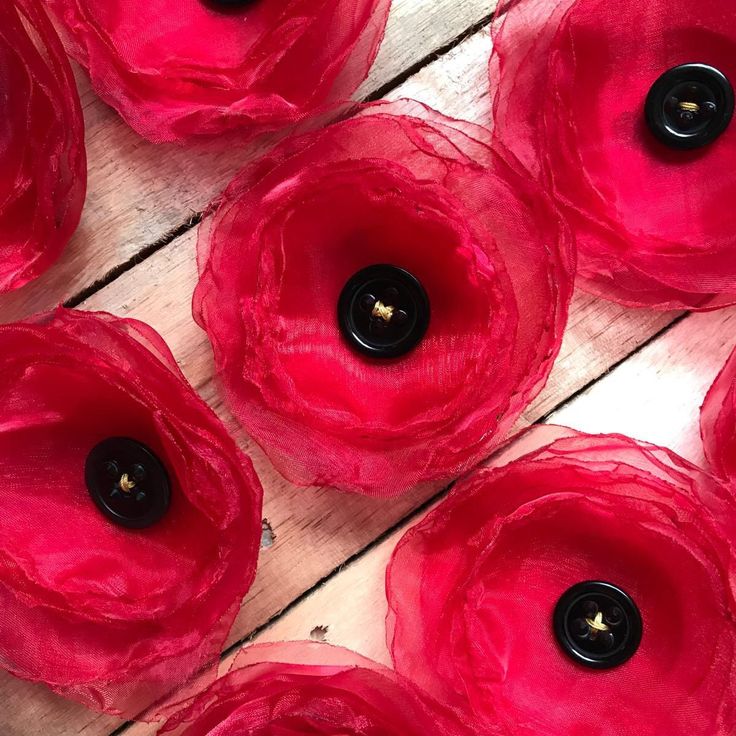 red flowers with black centers are arranged on a wooden surface, close up to the center