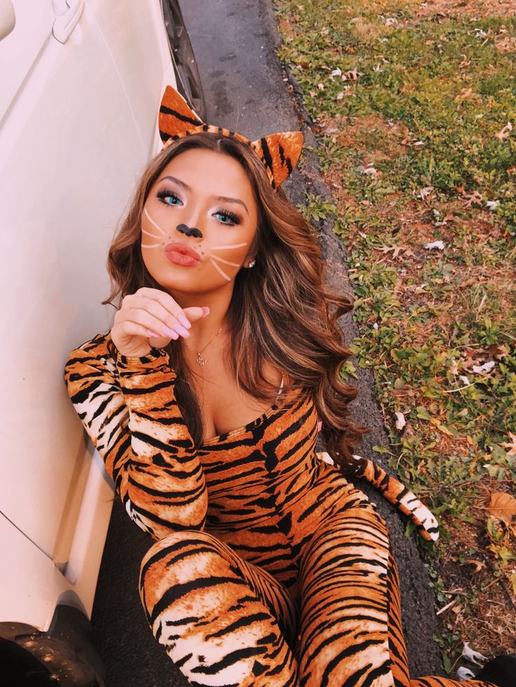 a woman in a tiger costume sitting next to a car