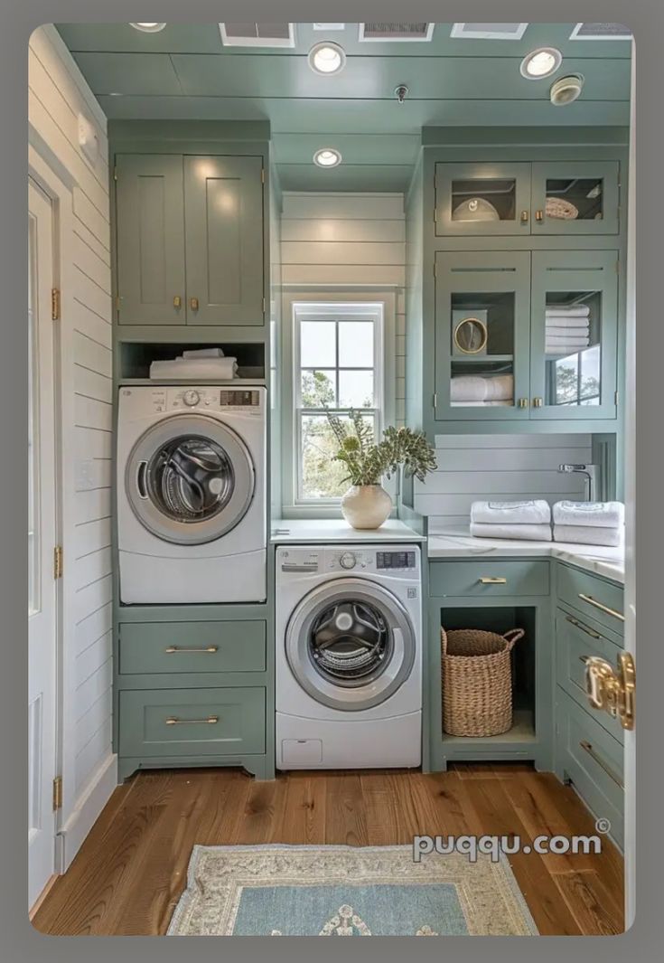 a washer and dryer in a small room with wood flooring, green cabinets and white walls