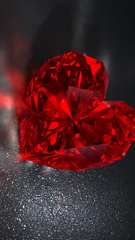 two heart shaped red diamonds sitting next to each other on a black surface with water droplets around them