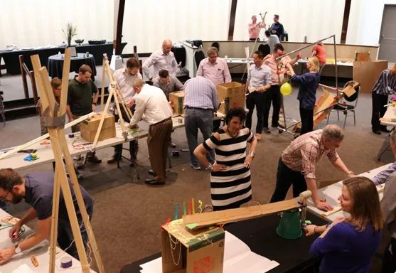 a group of people standing around each other in an art room with easels and paintings on the walls