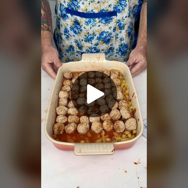 a woman holding a pan filled with meatballs and sauce on top of a table