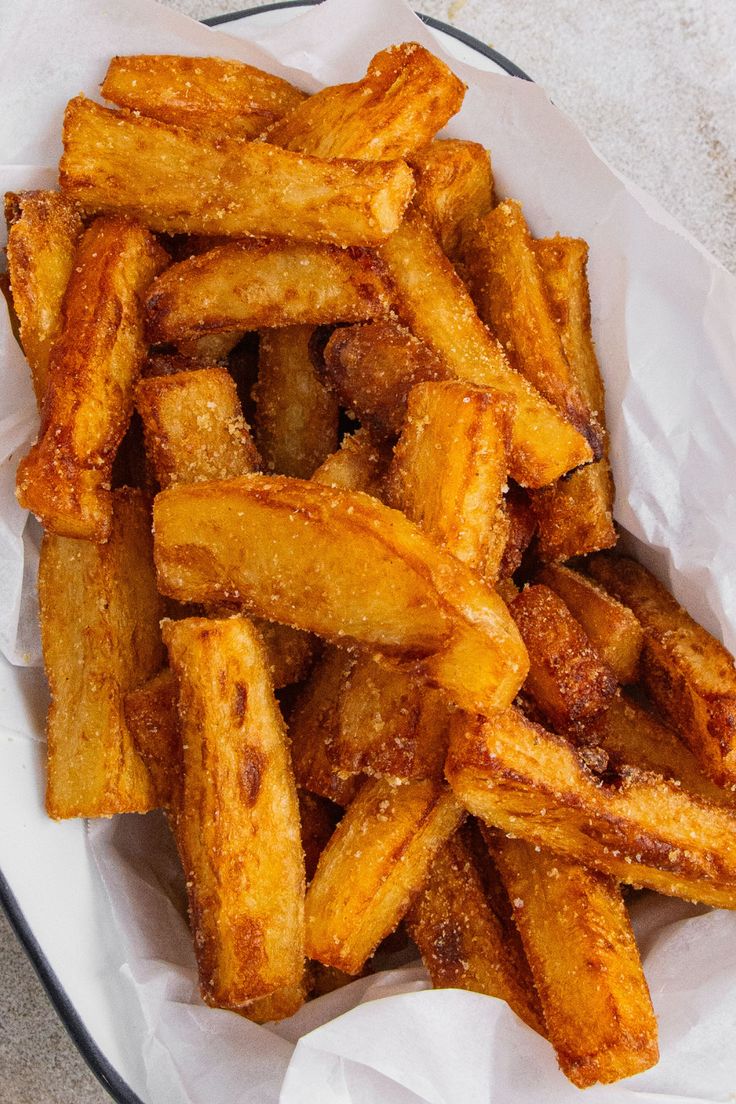 a plate full of french fries sitting on top of a white table cloth covered in wax paper