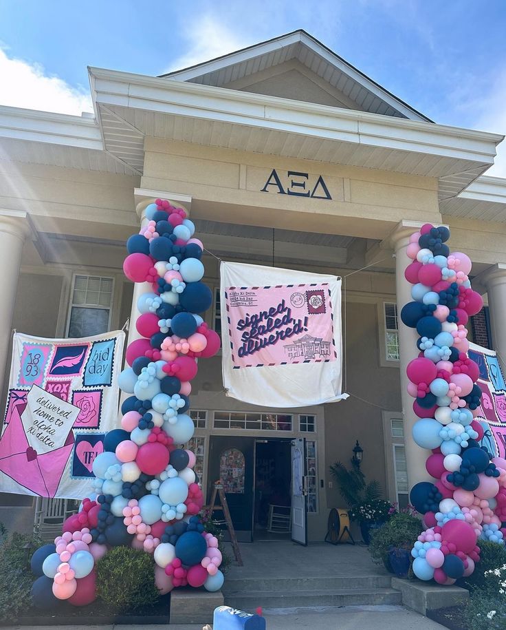 an entrance to a building decorated with balloons and streamers in the shape of letters