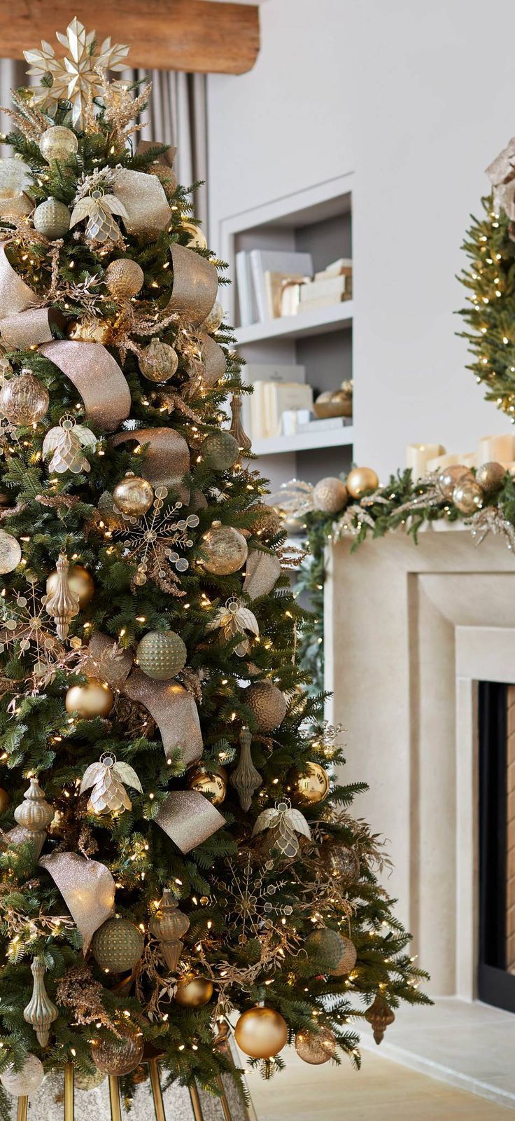 a decorated christmas tree in a living room with gold and silver ornaments on the top