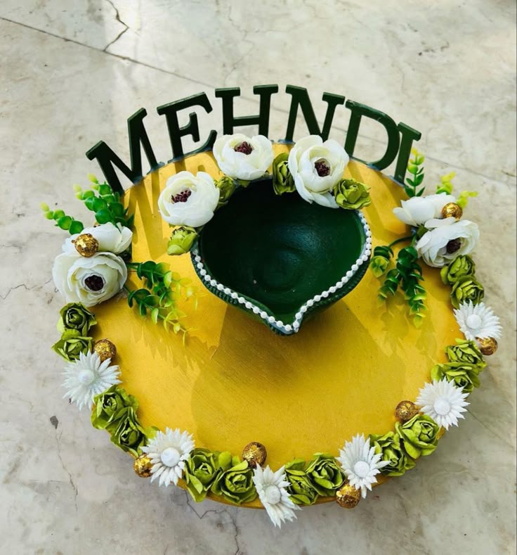 a cake decorated with flowers and the word mehndi written in green on top