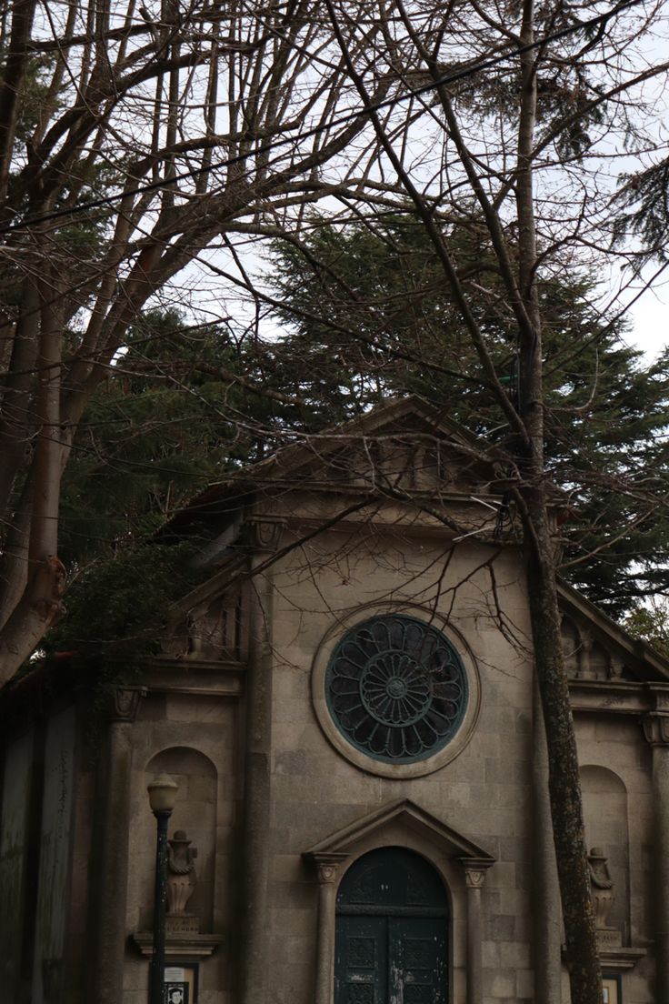 an old church with a clock on it's face and trees in the background