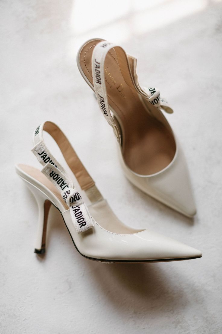 a pair of white high heeled shoes sitting on top of a floor