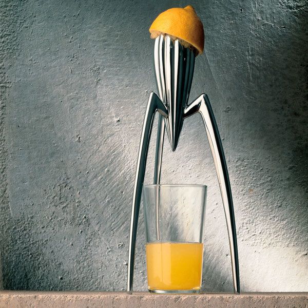 a glass filled with orange juice sitting on top of a counter next to a metal object