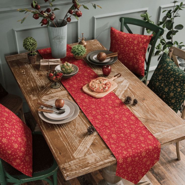 a wooden table topped with plates and bowls filled with food next to green chairs in front of a potted plant