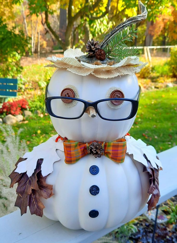 a white pumpkin with glasses and a hat on it's head sitting on a bench