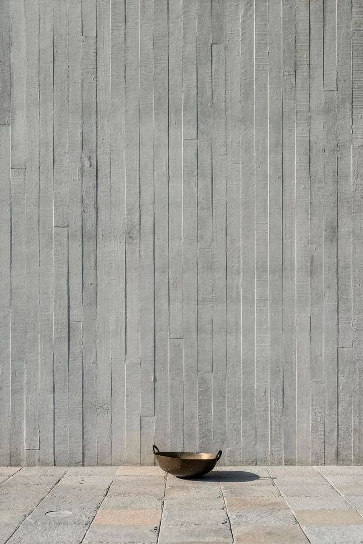 a bowl sitting on the ground in front of a wall