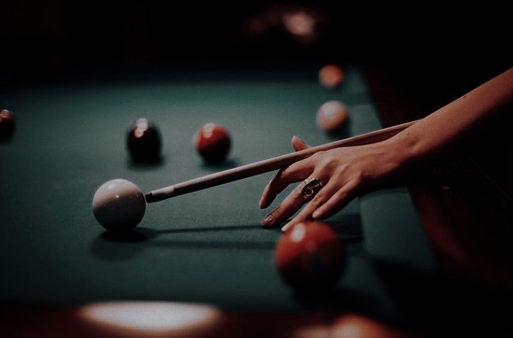 a woman's hand reaching for a pool ball