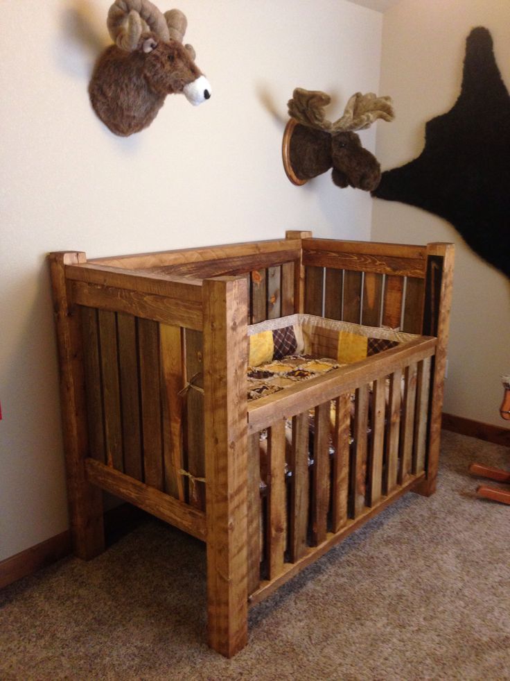 a baby crib with two stuffed animals on the wall above it and an animal head mounted to the wall