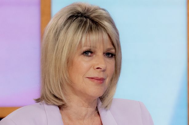 a woman with blonde hair is sitting in front of a tv screen and looking off to the side