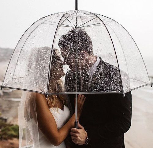 a bride and groom kissing under an umbrella