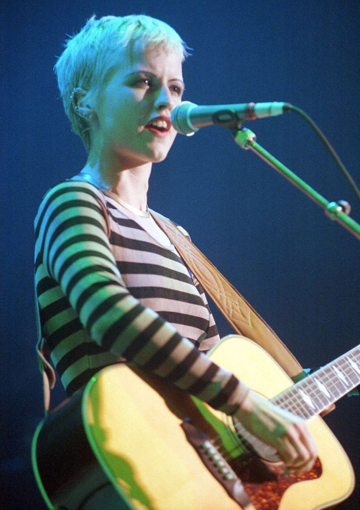 a woman singing into a microphone while holding a guitar