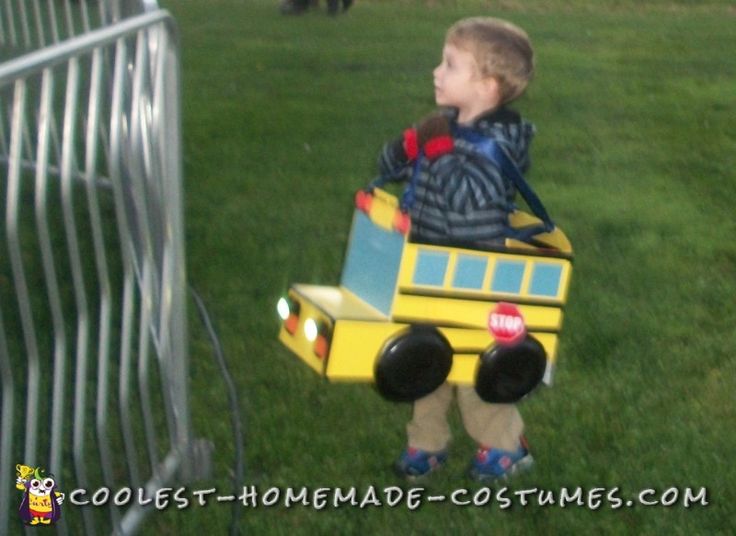 a little boy that is standing in the grass with a toy train on his back