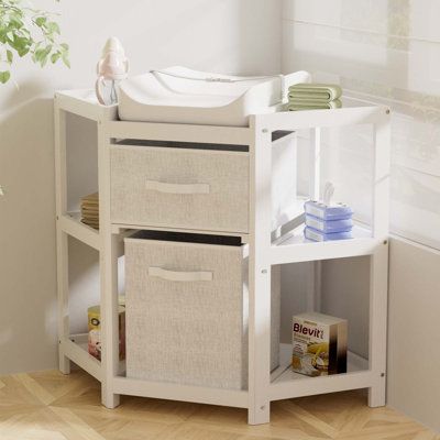 a white baby changing table with two baskets on the bottom and an open drawer underneath it