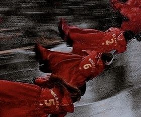 two people in red raincoats riding on skateboards