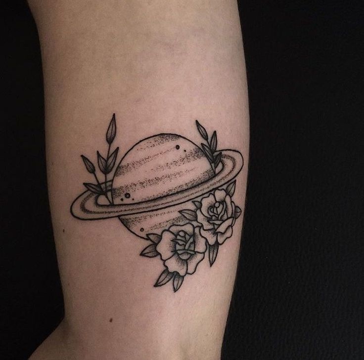 a black and white photo of a saturn tattoo on the right arm with roses around it