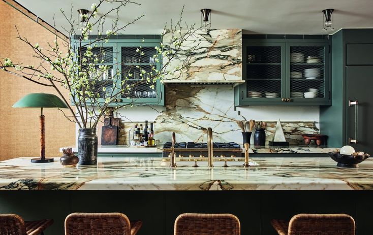 a kitchen with green cabinets and marble counter tops in the center island, surrounded by wicker chairs