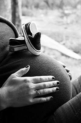 black and white photograph of a pregnant woman's belly with her hands on her stomach