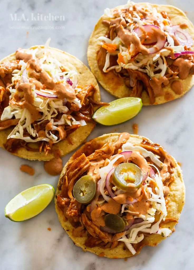 three tortillas topped with shredded cheese, sauce and pickles on a marble surface