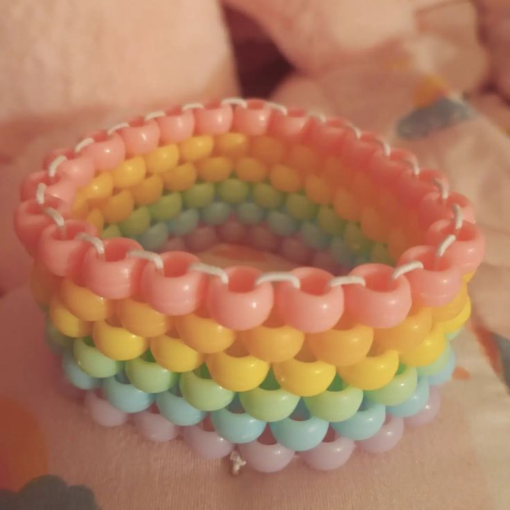 two bracelets with different colored beads on top of a table next to a teddy bear