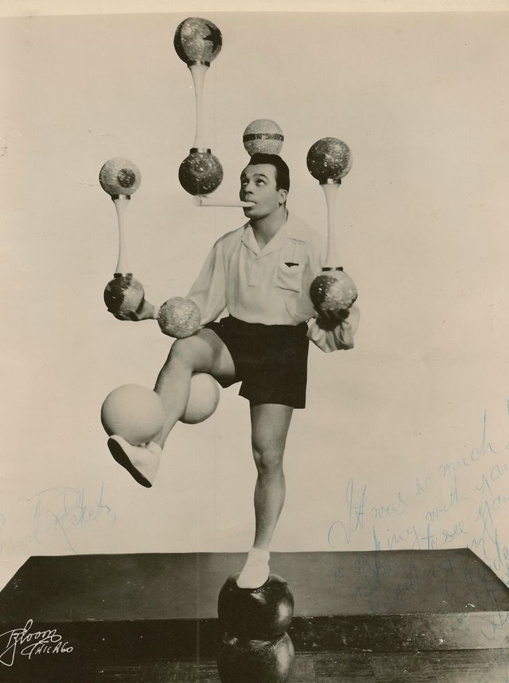 an old black and white photo of a man balancing balls on one leg with two hands