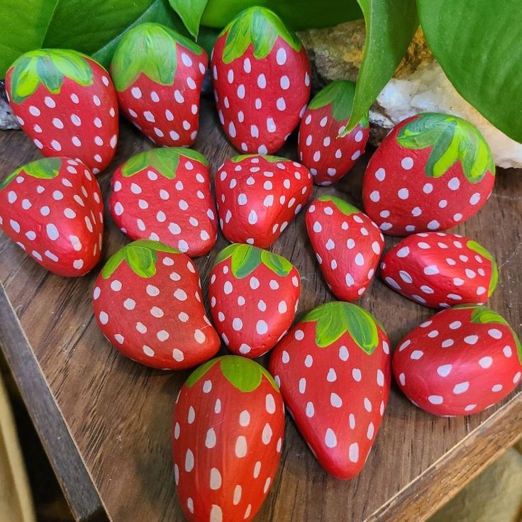 a group of strawberries sitting on top of a wooden table next to green leaves