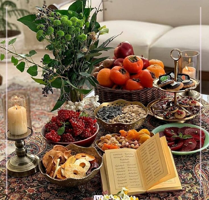 a table topped with lots of food and a book on it's side next to a vase filled with flowers