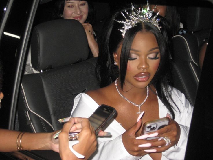 a woman in a white dress is looking at her cell phone while sitting in the back seat of a car